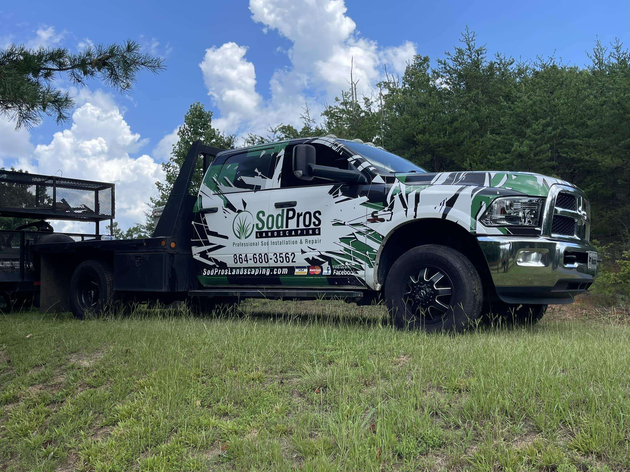 Sod Pros Landscaping truck parked in a grassy area, featuring branding and contact information for professional sod installation and repair services.