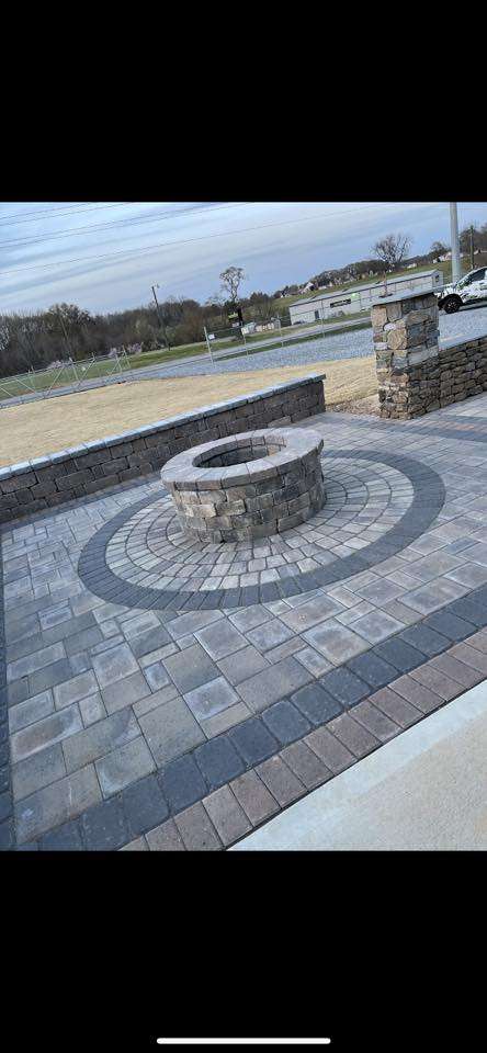 Custom stone fire pit surrounded by patterned paver patio, designed for outdoor cooking and gatherings, enhancing outdoor living spaces.