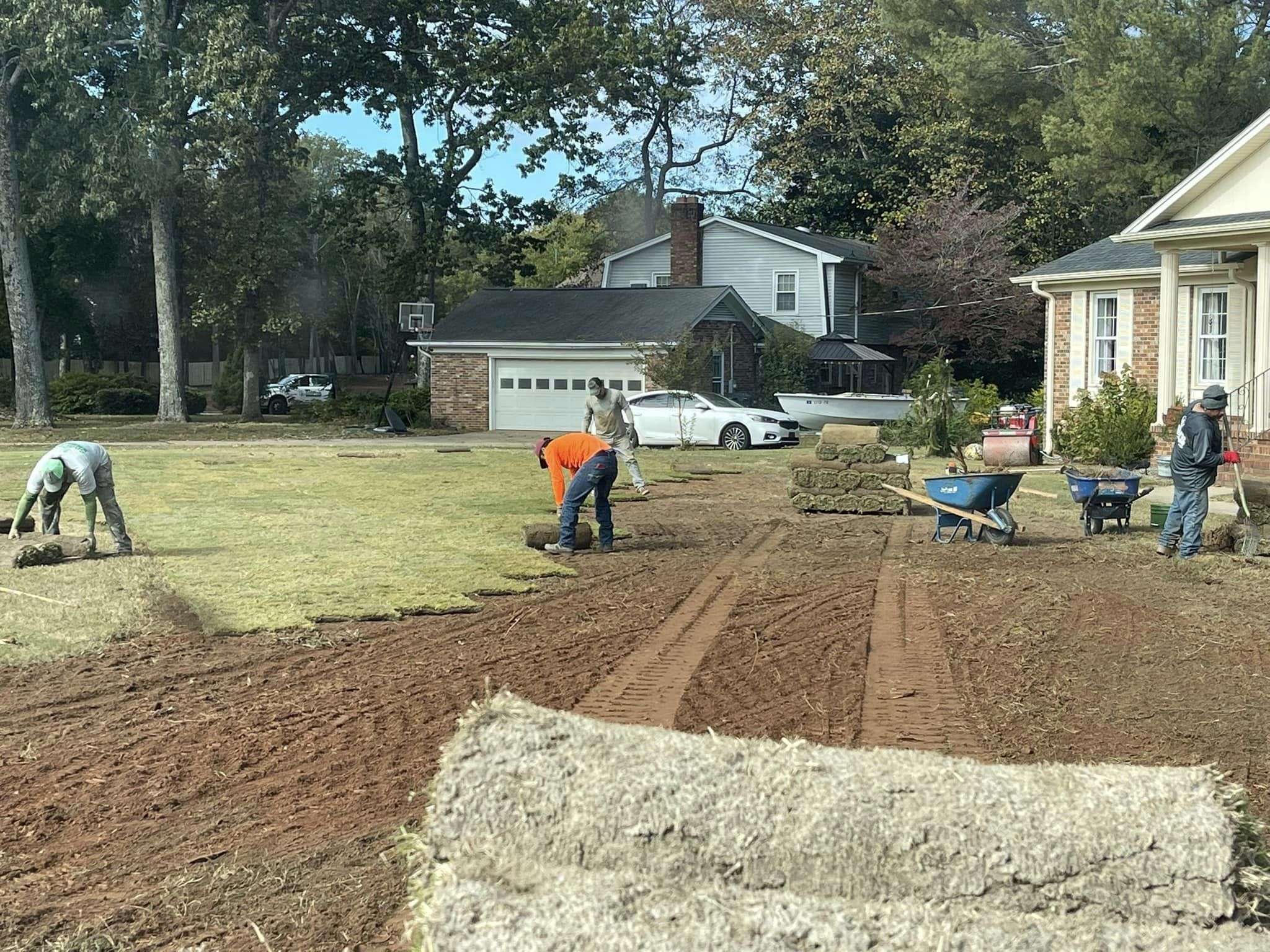 Landscapers installing sod in a residential yard, demonstrating professional landscaping services by Sod Pros Landscaping in Greenville, SC.
