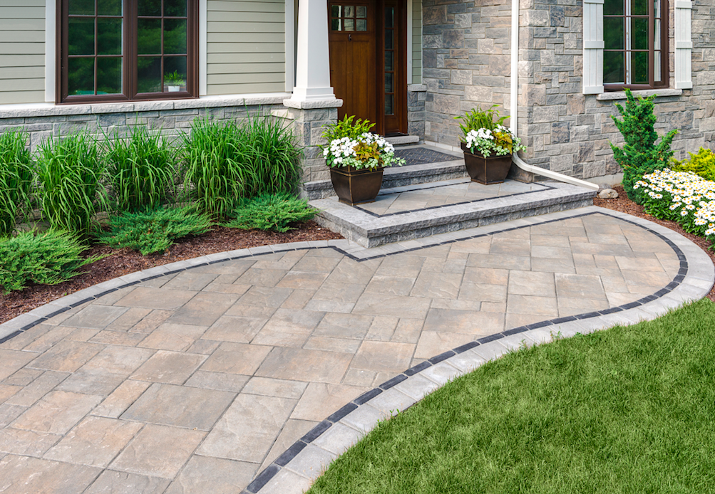 Paved outdoor patio with decorative stonework, flower pots, and landscaped greenery, showcasing professional hardscaping services by Sod Pros Landscaping in Spartanburg.