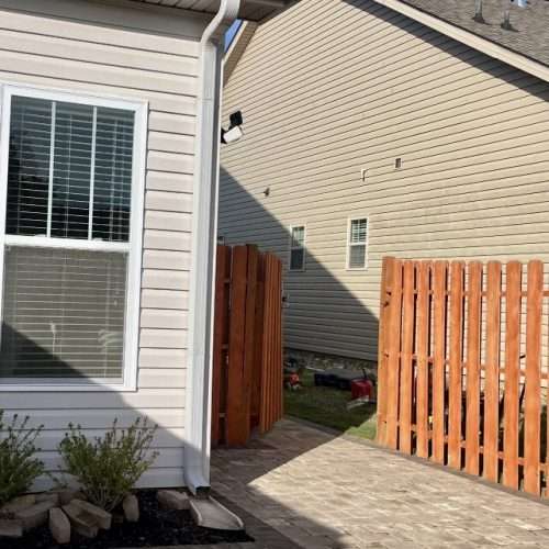 Patio installation featuring a wooden fence and stone pathway, enhancing outdoor living space for Sod Pros Landscaping services.