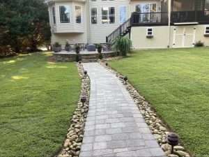 Paved walkway leading to a home with a lush green lawn and landscaped garden, illustrating effective sod installation and landscaping design.