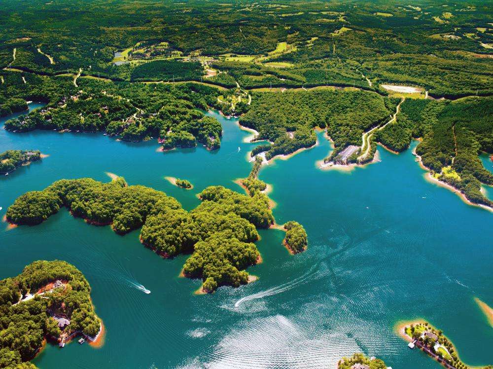 Aerial view of Lake Keowee showcasing lush green islands and clear blue water, emphasizing natural beauty and environmental benefits of landscaping.