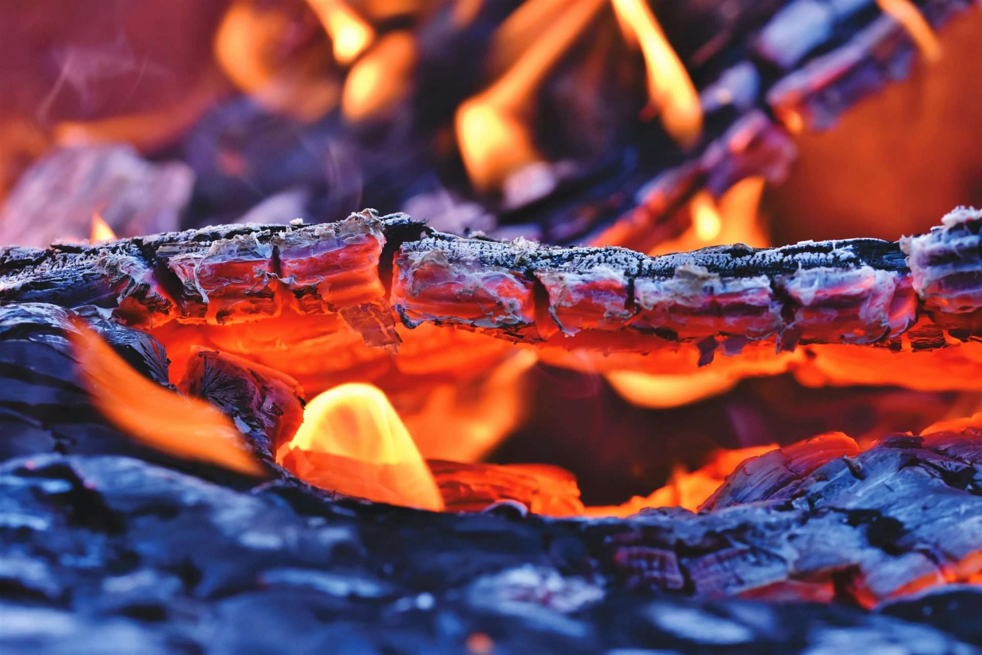 Close-up of glowing embers and flames from a fire pit, highlighting the warmth and inviting atmosphere for outdoor gatherings and cooking experiences.