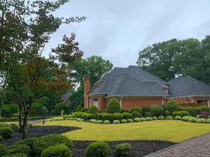 Lush green lawn and well-manicured shrubs surrounding a brick home, showcasing professional sod installation and landscaping design.